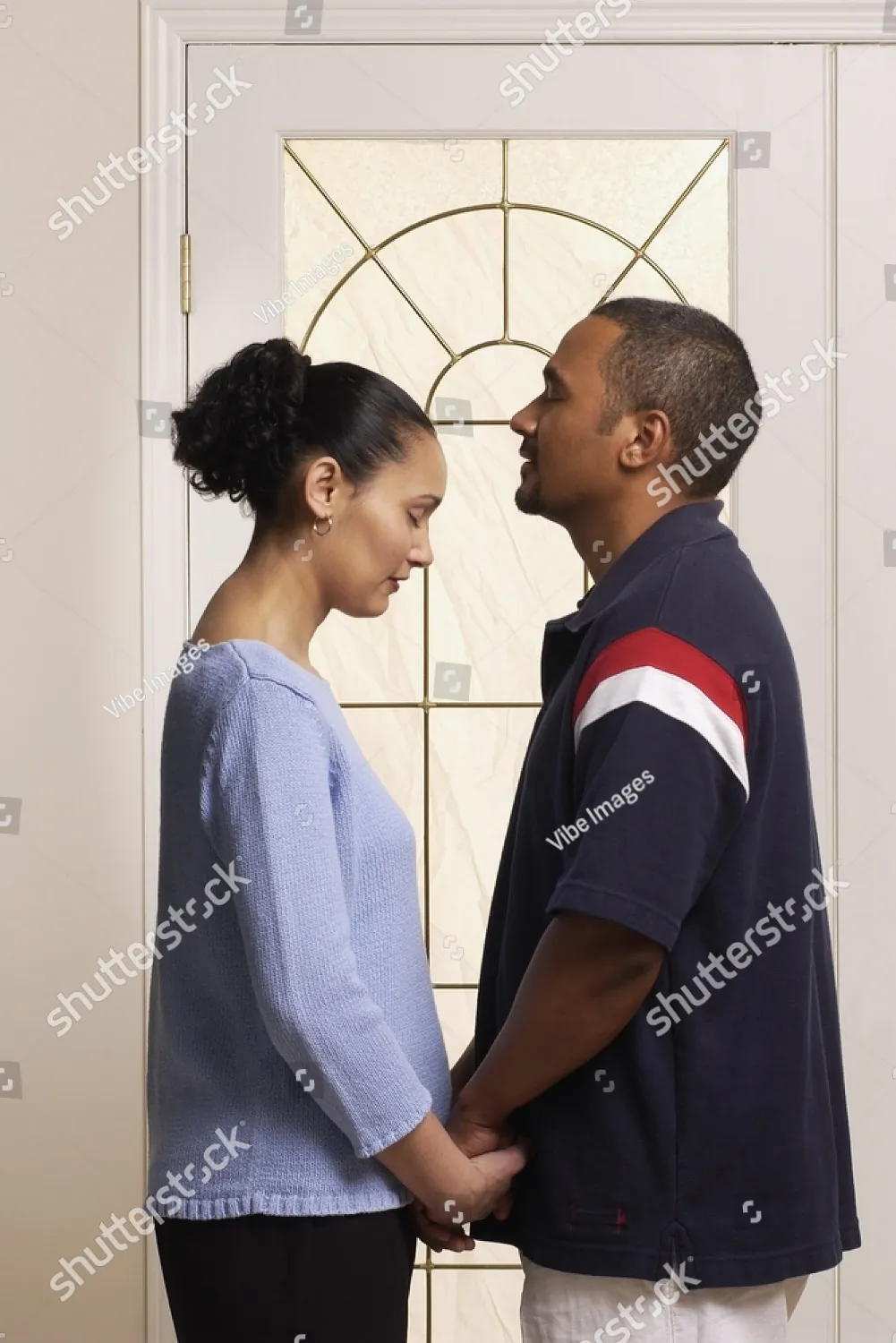 A couple holding hands, foreheads close, at the front door